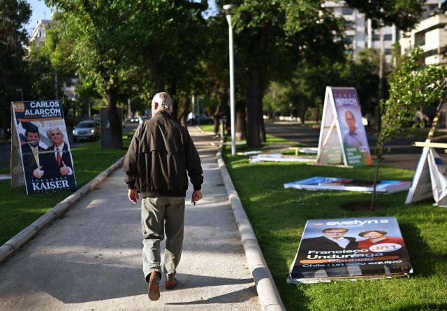 A man walks past electoral advertising posters in Santiago on November 10, 2025. Chile will hold presidential election on November 16. (Photo by RODRIGO ARANGUA / AFP)