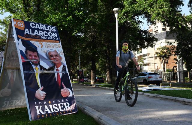 A man rides his bicycle next to electoral advertising posters in Santiago on November 10, 2025. Chile will hold presidential election on November 16. (Photo by RODRIGO ARANGUA / AFP)