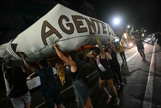 Activists march down a street carrying a snake-shaped puppet in Belem, Brazil, on November 10, 2025, during a protest organized by Oxfam Brazil and the Alliance of Peoples for Climate to mark the end of the first day of COP30. The COP30 runs from November 10 to 21, and the 50,000 participants will feel the heavy, humid air of the Amazon rainforest, and face the daunting task of keeping global climate cooperation from collapsing. (Photo by Mauro PIMENTEL / AFP)