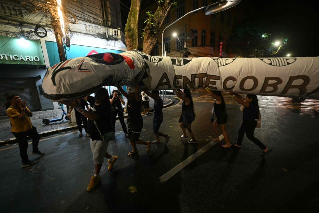 Activists march down a street carrying a snake-shaped puppet in Belem, Brazil, on November 10, 2025, during a protest organized by Oxfam Brazil and the Alliance of Peoples for Climate to mark the end of the first day of COP30. The COP30 runs from November 10 to 21, and the 50,000 participants will feel the heavy, humid air of the Amazon rainforest, and face the daunting task of keeping global climate cooperation from collapsing. (Photo by Mauro PIMENTEL / AFP)