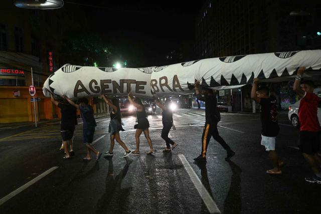 Activists march down a street carrying a snake-shaped puppet in Belem, Brazil, on November 10, 2025, during a protest organized by Oxfam Brazil and the Alliance of Peoples for Climate to mark the end of the first day of COP30. The COP30 runs from November 10 to 21, and the 50,000 participants will feel the heavy, humid air of the Amazon rainforest, and face the daunting task of keeping global climate cooperation from collapsing. (Photo by Mauro PIMENTEL / AFP)