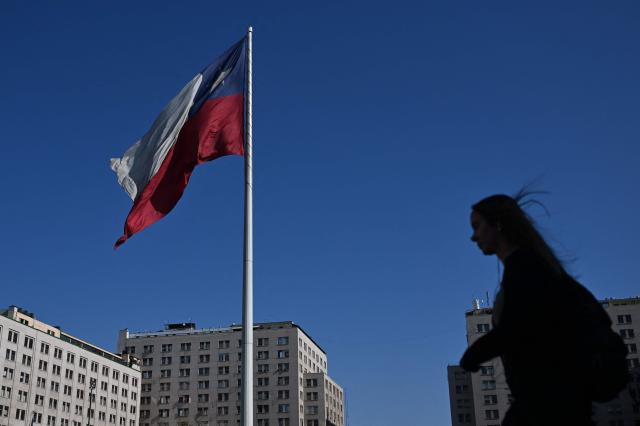 A woman walks past a Chilean flag near La Moneda Presidential palace in Santiago on November 10, 2025. Chile will hold presidential election on November 16. (Photo by Marvin RECINOS / AFP)
