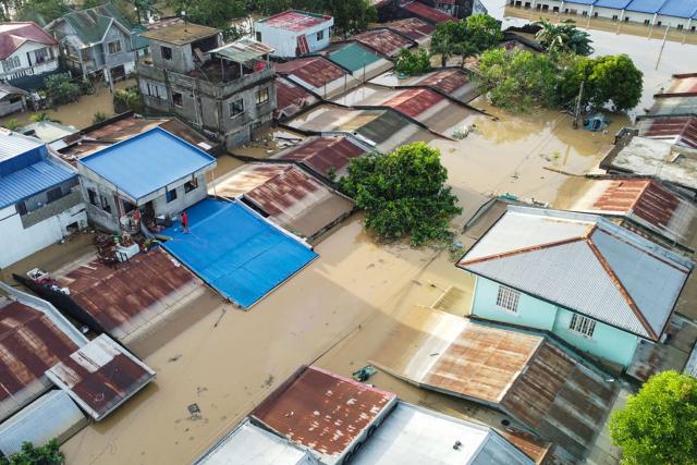 Residents stand on the roof of their flooded house in Ilagan City, Isabela province, north of Manila on November 11, 2025, as flood waters continue to inundate homes due to heavy rains brought about by Super Typhoon Fung-wong. Entire villages lay submerged and scores of towns remained without electricity on November 10 as Typhoon Fung-wong left the Philippines after killing at least five people and displacing more than a million. (Photo by Villamor VISAYA / AFP)