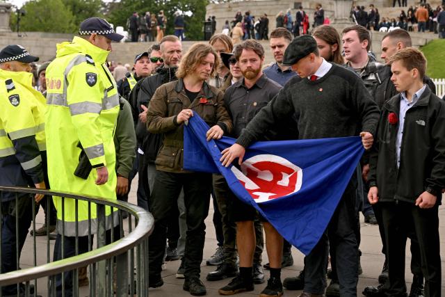 Members of the neo-Nazi National Socialist Network (NSN) fold up a flag after police intervened after a Remembrance Day service at Melbourne's Shrine of Remembrance on November 11, 2025. Each year on November 11 Australians mark Remembrance Day during which they observe a one minute's silence on the 11th hour of the 11th day of the 11th month to honour all who have served, suffered, or died in wars, conflicts, and peacekeeping operations. (Photo by William WEST / AFP)