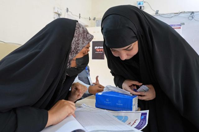 Iraqi polling officials look at a voter's list inside a polling station in the Al-Amir neighbourhood of Najaf district on November 11, 2025 during Iraq's parliamentary elections. Iraq is holding parliamentary elections, with analysts saying Iran will be watching closely as it hopes to retain influence over its neighbour after losing regional leverage during the Gaza war. (Photo by Qassem al-KAABI / AFP)