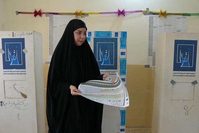 An Iraqi voter holds the ballot paper after casting her vote at a polling station in the Al-Amir neighbourhood of Najaf district on November 11, 2025 during Iraq's parliamentary elections. Iraq is holding parliamentary elections, with analysts saying Iran will be watching closely as it hopes to retain influence over its neighbour after losing regional leverage during the Gaza war. (Photo by Qassem al-KAABI / AFP)