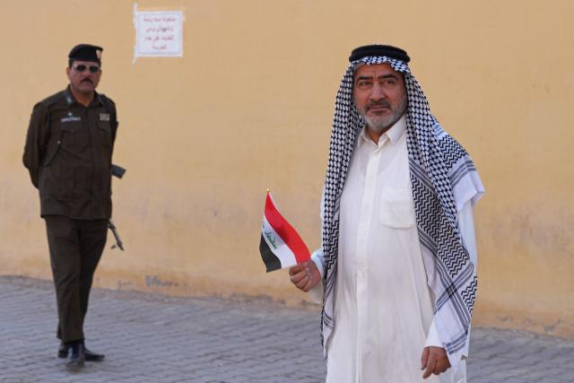 An Iraqi voter holds his country's national flag after casting his ballot at a polling station in the Al-Amir neighbourhood of Najaf district on November 11, 2025 during Iraq's parliamentary elections. Iraq is holding parliamentary elections, with analysts saying Iran will be watching closely as it hopes to retain influence over its neighbour after losing regional leverage during the Gaza war. (Photo by Qassem al-KAABI / AFP)