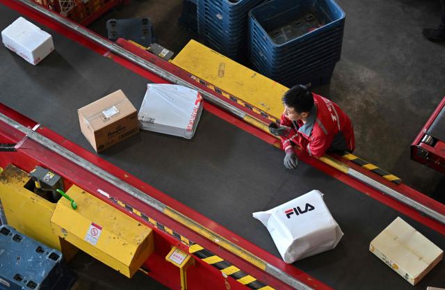 A worker sorts packages at JD's warehouse during the double 11 festival or Singles's Day, China's massive annual shopping event in Beijing on November 11, 2025. (Photo by Adek BERRY / AFP)