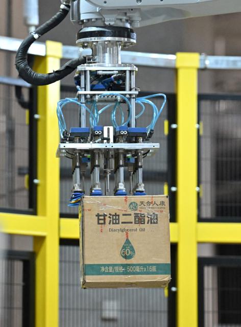 A robot lifts a package at JD's warehouse during the double 11 festival or Singles's Day, China's massive annual shopping event in Beijing on November 11, 2025. (Photo by Adek BERRY / AFP)