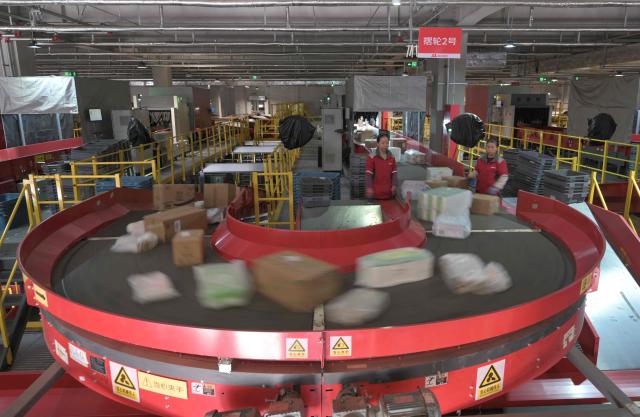 Workers sort packages at JD's warehouse during the double 11 festival or Singles's Day, China's massive annual shopping event in Beijing on November 11, 2025. (Photo by Adek BERRY / AFP)
