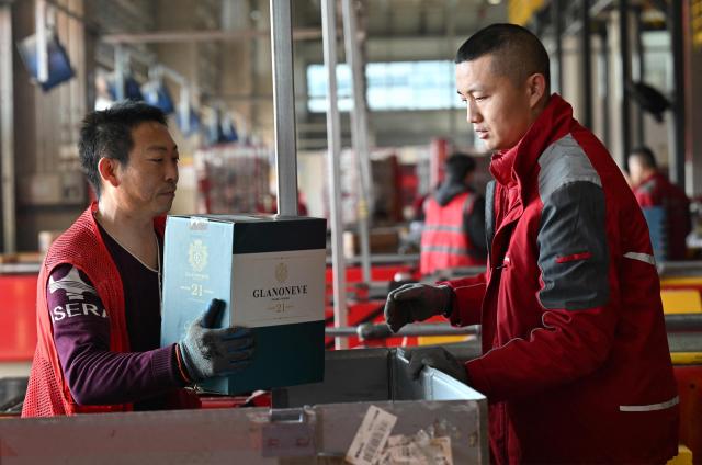 Workers sort packages at JD's warehouse during the double 11 festival or Singles's Day, China's massive annual shopping event in Beijing on November 11, 2025. (Photo by Adek BERRY / AFP)