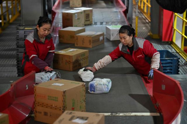 Workers sort packages at JD's warehouse during the double 11 festival or Singles's Day, China's massive annual shopping event in Beijing on November 11, 2025. (Photo by Adek BERRY / AFP)