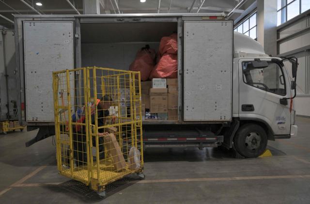 A worker uploads packages into a truck at JD's warehouse during the double 11 festival or Singles's Day, China's massive annual shopping event in Beijing on November 11, 2025. (Photo by Adek BERRY / AFP)