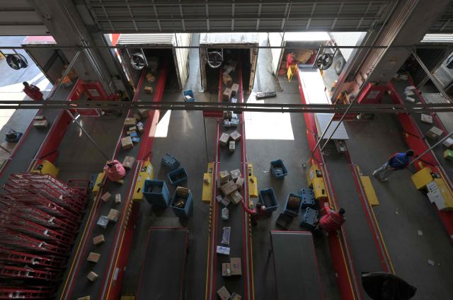 Workers sort packages at JD's warehouse during the double 11 festival or Singles's Day, China's massive annual shopping event in Beijing on November 11, 2025. (Photo by Adek BERRY / AFP)