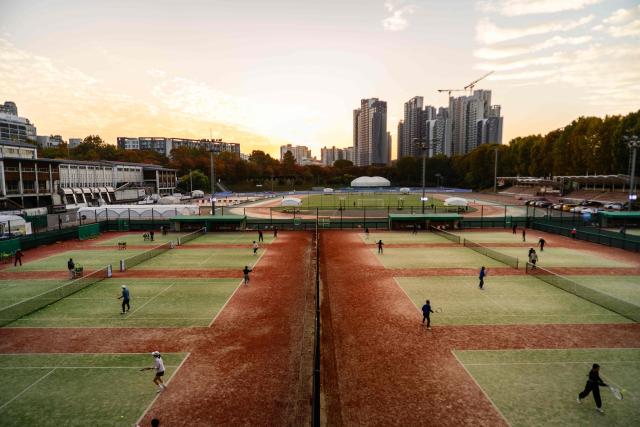 People play tennis at a public sports ground as the sun sets in Seoul on November 11, 2025. (Photo by ANTHONY WALLACE / AFP)