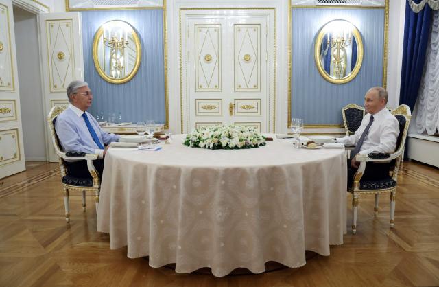 In this pool photograph distributed by the Russian state agency Sputnik, Russian President Vladimir Putin and Kazakh President Kassym-Jomart Tokayev hold an informal dinner at the Kremlin in Moscow on November 11, 2025. (Photo by Vyacheslav PROKOFYEV / POOL / AFP)