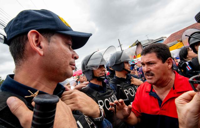 A man speaks with a member of the Costa Rican Police during a march against the government of Rodrigo Chaves, accused of attacking democracy, in San Jose on November 11, 2025. (Photo by Ezequiel BECERRA / AFP)