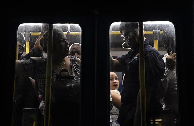 People travel by bus during a nationwide blackout in Santo Domingo on November 11, 2025. Santa Domingo found itself without electricity Tuesday as the Dominican Republic's energy company announced a blackout of unspecified scope, caused by a "transmission system failure." (Photo by Eddy Vittini / AFP)