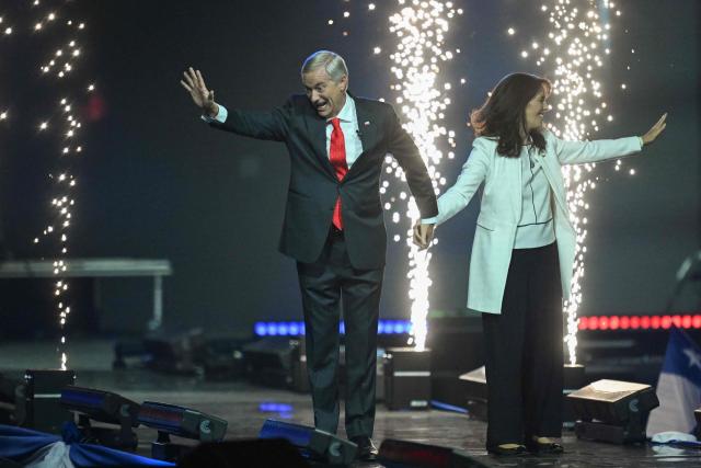 Chile's presidential candidate Jose Antonio Kast of the Republican Party and his wife  Maria Pia Adriasola greet supporters during his closing campaign rally at Movistar Arena in Santiago on November 11, 2025. Chile will hold the presidential election on November 16, 2025. (Photo by MARVIN RECINOS / AFP)