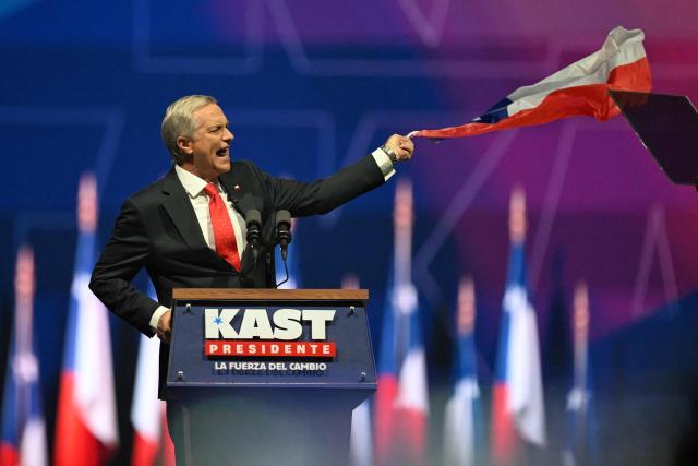 Chile's presidential candidate Jose Antonio Kast of the Republican Party speaks while holding a national flag during his closing campaign rally at Movistar Arena in Santiago on November 11, 2025. Chile will hold the presidential election on November 16, 2025. (Photo by MARVIN RECINOS / AFP)