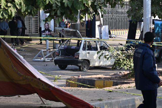 Police officials inspect the cordoned-off site, a day after the suicide bombing, in Islamabad on November 12, 2025. Charred vehicles and a mangled motorcycle lay outside Islamabad's district court on November 11, their metal frames still warm as investigators sealed off the area where a suicide bomber had killed at least 12 people. (Photo by Aamir QURESHI / AFP)