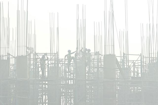 Labourers work at a construction site, amid smog in Amritsar on November 12, 2025. (Photo by Narinder NANU / AFP)