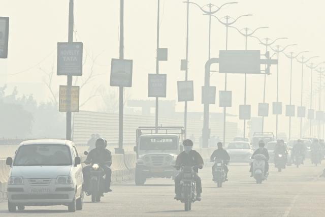 Commuters drive amid smog in Amritsar on November 12, 2025. (Photo by Narinder NANU / AFP)