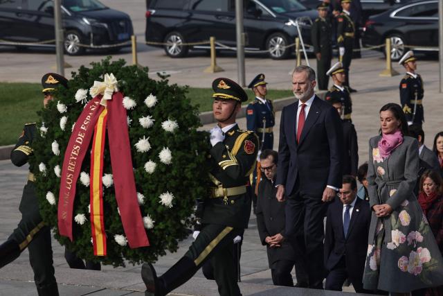 Spain's King Felipe VI (2 R) and Queen Letizia (R) walk following members of the honour guard during a flower wreath ceremony at the Monument to the People's Heroes, in Tiananmen Square, in Beijing on November 12, 2025. (Photo by ANDRES MARTINEZ CASARES / EPA-POOL / AFP)