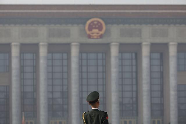 A member of the honour guard stands in front of the Great Hall of the People from the Monument to the People's Heroes, in Tiananmen Square, in Beijing on November 12, 2025. (Photo by ANDRES MARTINEZ CASARES / EPA-POOL / AFP)