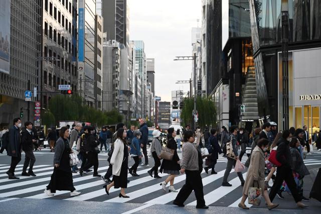 People cross a road in Ginza, in Tokyo on November 12, 2025. (Photo by GREG BAKER / AFP)