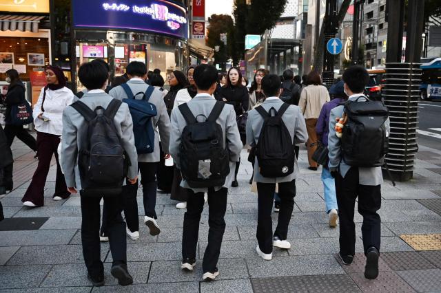 Schoolboys walk on a street in Ginza, in Tokyo on November 12, 2025. (Photo by GREG BAKER / AFP)
