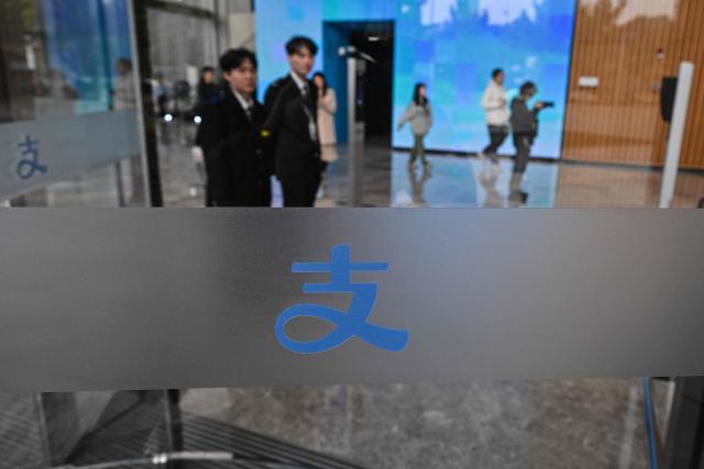 People walk in the headquarters of Chinese digital payments platform Alipay in the Pudong district in Shanghai on November 12, 2025. (Photo by Hector RETAMAL / AFP)