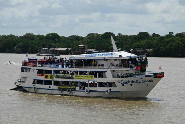 View of a boat taking part in a trip of indigenous people and social organizations in the sidelines of the COP30 UN Climate Change Conference in Belem, Para State, Brazil, on November 12, 2025. Over 150 boats with members of indigenous communities and social organizations will sail the Guama River as part of a symbolic crossing during the COP30, according to organizers. (Photo by Pablo PORCIUNCULA / AFP)