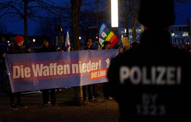 Supporters of Germany's The Left (Die Linke) party protest with an anti-war banner nearby a presentation of military equipment of the German armed forces on the occasion of the 70th anniversary of the Bundeswehr, in the center of Munich, southern Germany on November 12, 2025. (Photo by Michaela STACHE / AFP)