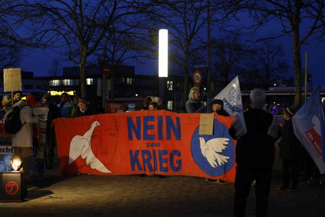 Protesters hold anti-war banners nearby a presentation of military equipment of the German armed forces on the occasion of the 70th anniversary of the Bundeswehr, in the center of Munich, southern Germany on November 12, 2025. (Photo by Michaela STACHE / AFP)
