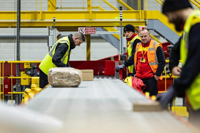 Employees put parcels on a line at a DHL warehouse in Lesquin, near Lille, on November 12, 2025. (Photo by Sameer Al-DOUMY / AFP)