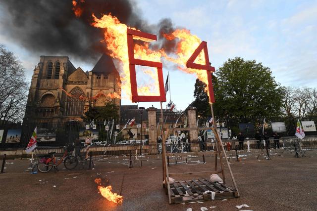 (FILES) A photo shows a wooden construction reading "64" set afire outside the Sarthe prefecture during a demonstration after France's Constitutional Council approved the key elements of a pension reform, in Le Mans, western France, on April 14, 2023. On November 12, 2025, the National Assembly broadly approved the ‘suspension’ of pension reform, a prerequisite for the Socialists not to censure Sйbastien Lecornu's government.
The measure, included in the 2026 Social Security budget bill, was approved by 255 votes to 146, with majority support from the PS, the ecologists and the RN, and abstention from Renaissance MPs. (Photo by JEAN-FRANCOIS MONIER / AFP)