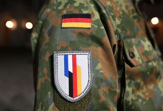 Badges showing the German flag (top) and the emblem of the Franco-German Brigade are seen on the uniform of a soldier during the solemn oath ceremony for recruits at Ludwigsburg Castle in Ludwigsburg, southwestern Germany, on November 12, 2025. 250 recruits of the Artillery Bataillon 295 and the Hunter Bataillon 292 take their solemn oath on the 70th anniversary of the founding of the German armed forces Bundeswehr. (Photo by THOMAS KIENZLE / AFP)