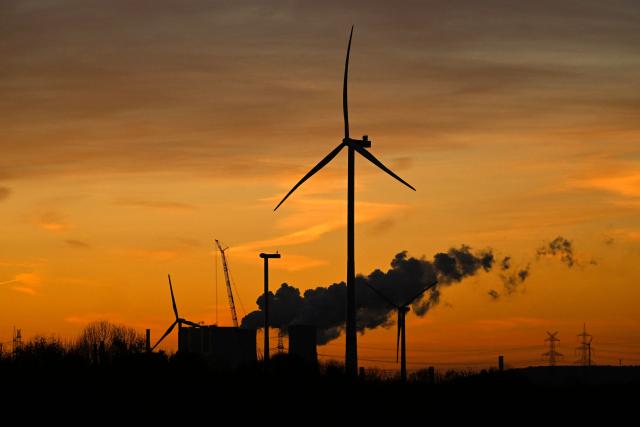 This picture taken at sunset on November 12, 2025 shows wind turbines near the lignite-fired power station operated by German energy giant RWE near Neurath, western Germany. (Photo by Ina FASSBENDER / AFP)