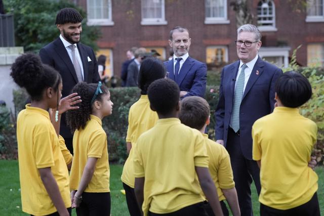 Britain's Prime Minister Keir Starmer (R), UEFA president Aleksander Ceferin (C) and England football player Tyrone Mings (L) chat with children from "John Keble C of E" primary school at 10 Downing Street in London on November 12, 2025, during a visit by UEFA officials to mark the launch of UEFA Euro 2028. The UEFA Euro 2028 tournament is set to be jointly hosted by the United Kingdom and Ireland. (Photo by Stefan Rousseau / POOL / AFP)