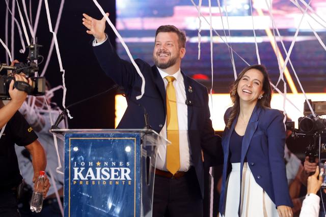 Chile's presidential candidate Johannes Kaiser (L) of the Libertarian National Party and his wife Ivette Avaria Vera (R) greet supporters during his closing campaign rally in Santiago on November 12, 2025. (Photo by Raul BRAVO / AFP)
