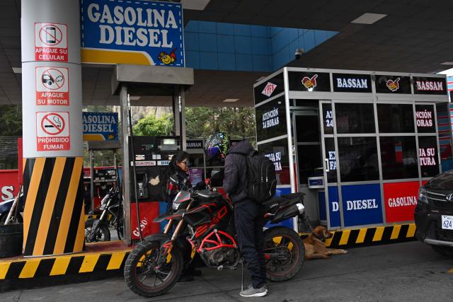 A motorcyclist refuels at a gas station in La Paz on November 12, 2025. Lines of cars and buses waiting to refuel at gas stations begin to shrink in Bolivia after more than two years of shortages, following measures by the new government of Rodrigo Paz. (Photo by Aizar RALDES / AFP)