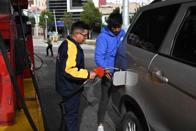 A gas station worker refuels a vehicle in La Paz on November 12, 2025. Lines of cars and buses waiting to refuel at gas stations begin to shrink in Bolivia after more than two years of shortages, following measures by the new government of Rodrigo Paz. (Photo by Aizar RALDES / AFP)