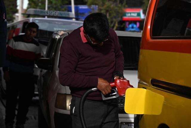 A man refuels at a gas station in La Paz on November 12, 2025. Lines of cars and buses waiting to refuel at gas stations begin to shrink in Bolivia after more than two years of shortages, following measures by the new government of Rodrigo Paz. (Photo by Aizar RALDES / AFP)