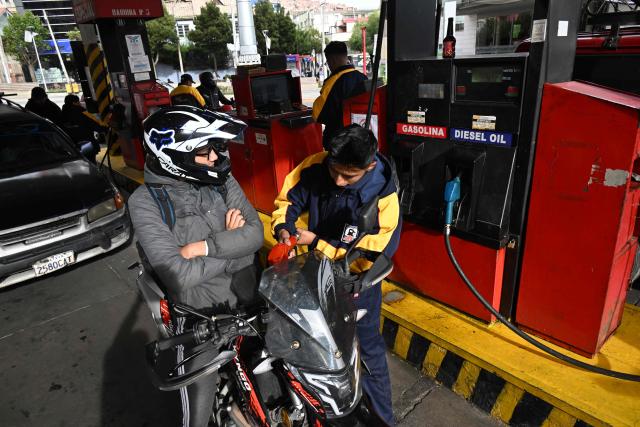 A gas station worker refuels a motorcycle in La Paz on November 12, 2025. Lines of cars and buses waiting to refuel at gas stations begin to shrink in Bolivia after more than two years of shortages, following measures by the new government of Rodrigo Paz. (Photo by Aizar RALDES / AFP)