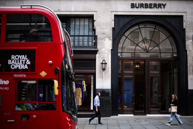 (FILES) Pedestrians walk past a double-decker bus and the store of British fashion label Burberry in central London on September 2, 2024. Burberry said on November 13, 2025 it narrowed losses in its first half thanks to the British luxury fashion label's turnaround plan begun a year ago. Its net loss stood at 26 million pounds (34 million USD) in the six months to the end of September, down on a loss after tax of 74 million pounds one year earlier. (Photo by HENRY NICHOLLS / AFP)