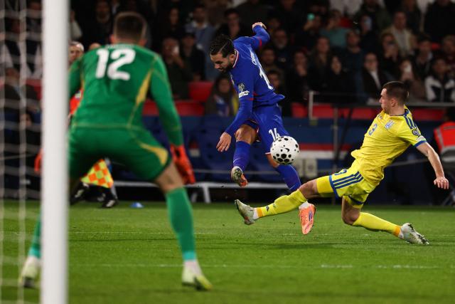 France's forward #14 Rayan Cherki (C) shoots the ball past Ukraine's defender #03 Bogdan Mykhailichenko (R) in front of Ukraine's goalkeeper #12 Anatoliy Trubin (L)v during the 2026 World Cup qualifiers Europe zone group D football match between France and Ukraine at the Parc des Princes stadium in Paris, on November 13, 2025. (Photo by FRANCK FIFE / AFP)