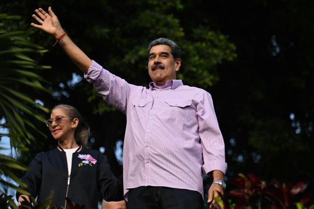 Venezuela's President Nicolas Maduro (R) waves next to his wife Cilia Flores (L) during a demonstration on Youth Day in Caracas on November 13, 2025. (Photo by Juan BARRETO / AFP)