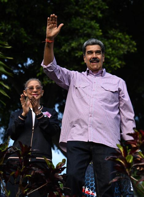 Venezuela's President Nicolas Maduro (R) waves next to his wife Cilia Flores (L) during a demonstration on Youth Day in Caracas on November 13, 2025. (Photo by Juan BARRETO / AFP)