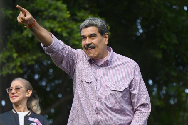 Venezuela's President Nicolas Maduro (R) gestures next to his wife Cilia Flores (L) during a demonstration on Youth Day in Caracas on November 13, 2025. (Photo by Juan BARRETO / AFP)